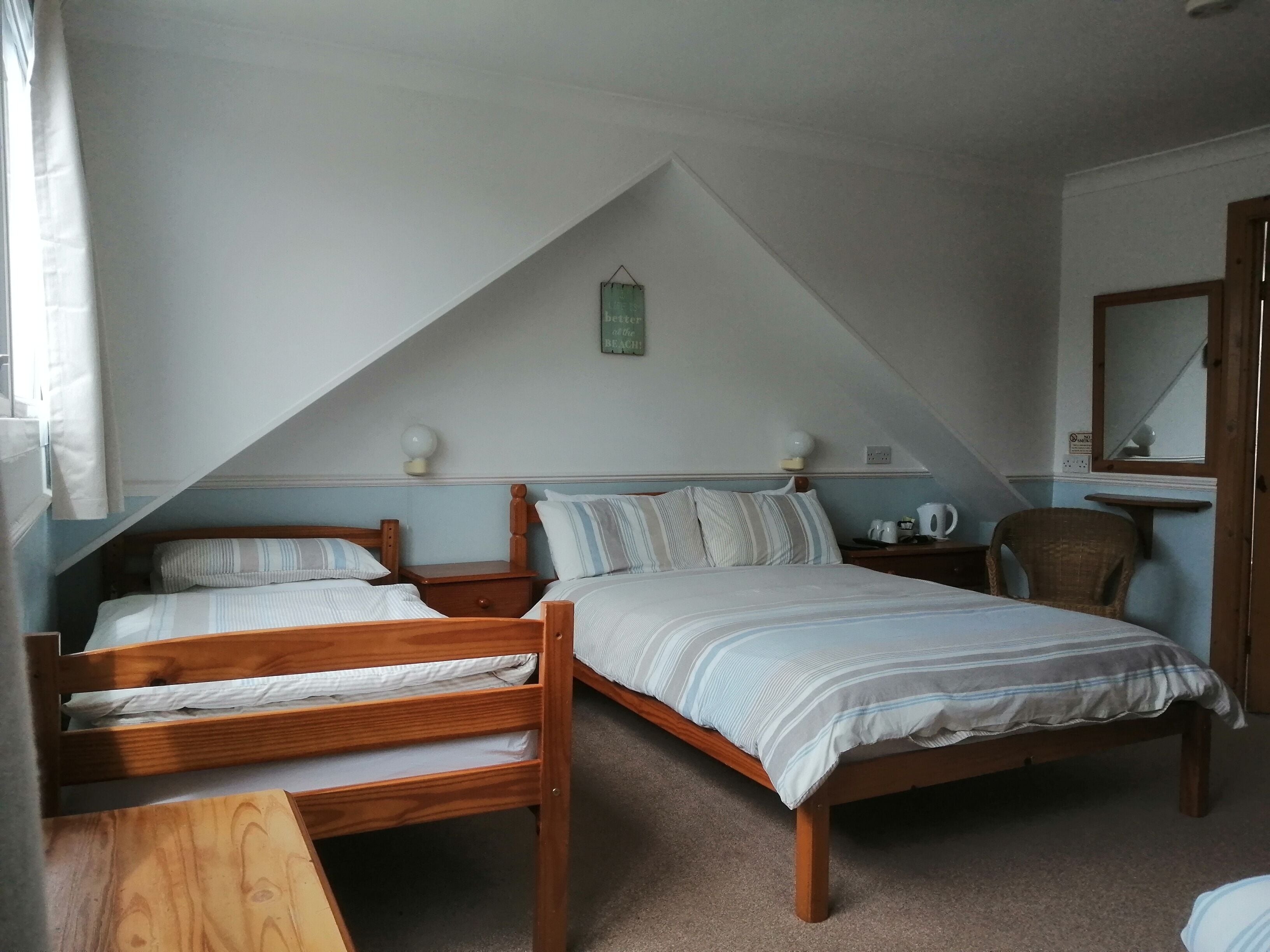 A bedroom with two wooden beds, a nightstand, a chair, and a small table.