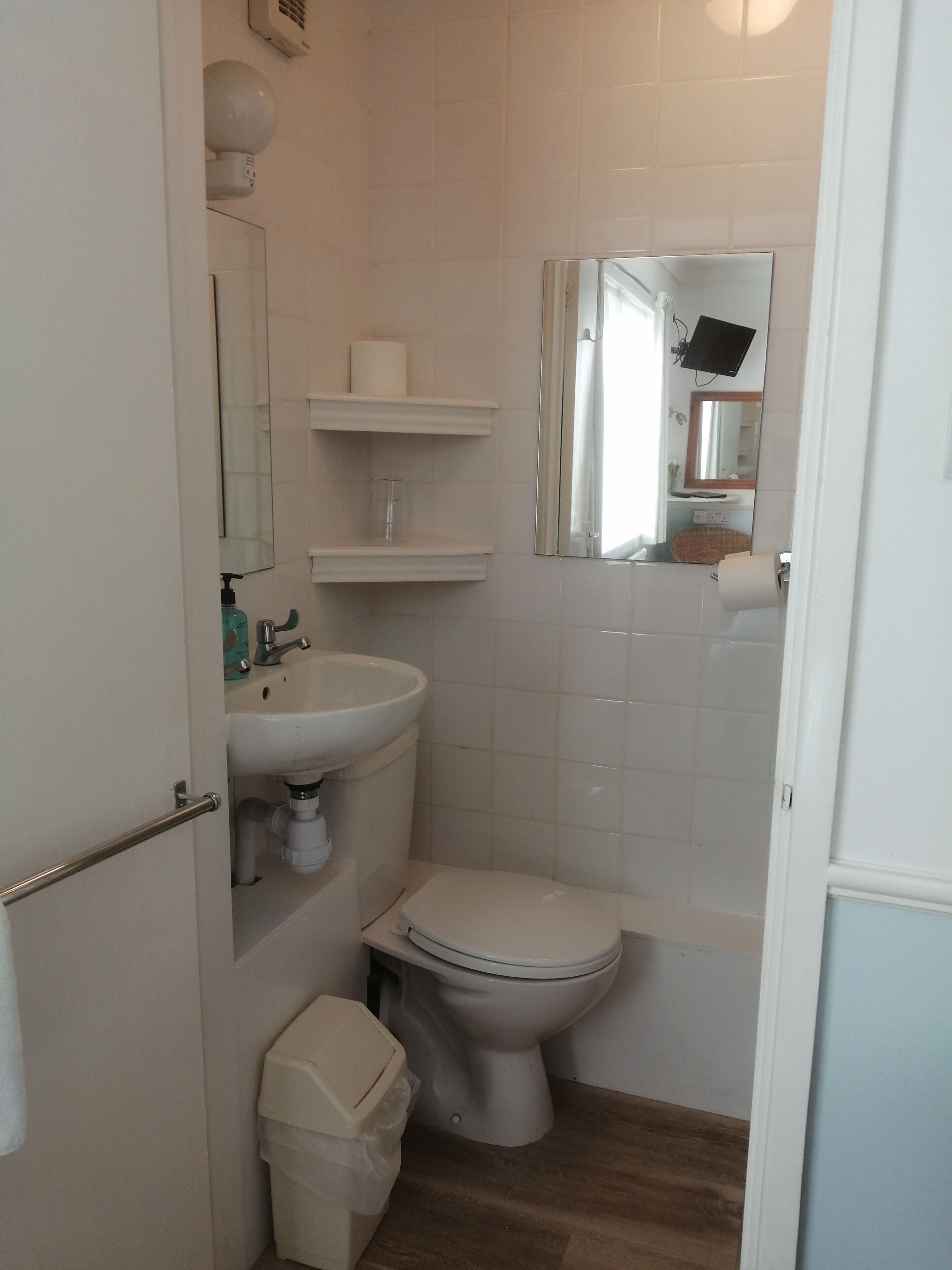 Une petite salle de bain comprenant des toilettes, un lavabo et un miroir.
