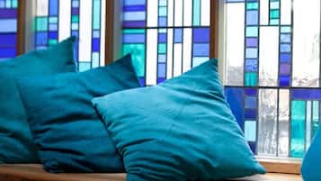 A window with stained glass, a wooden ledge, and a teal cushion.