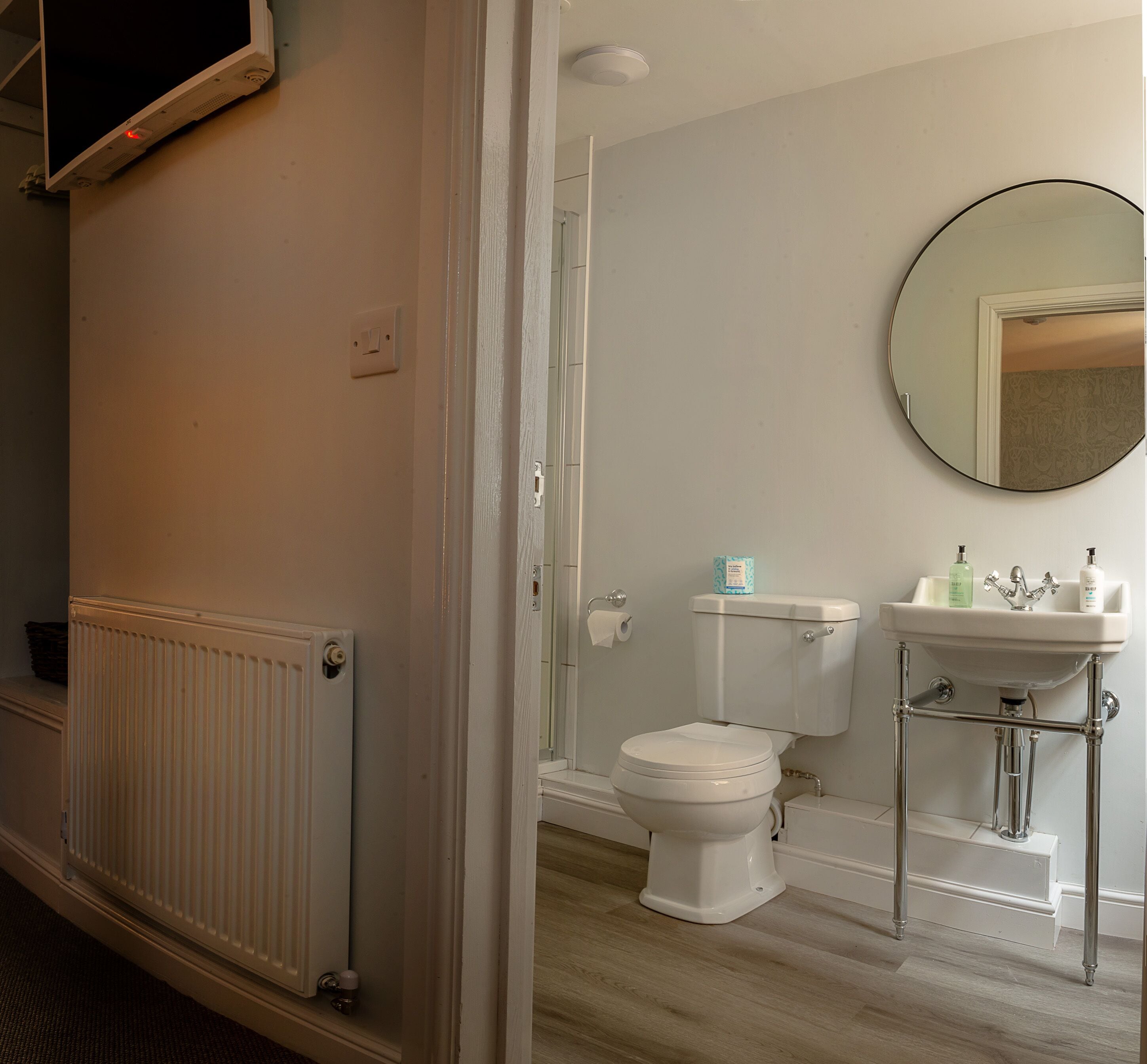 A bathroom with a toilet, sink, and mirror.
