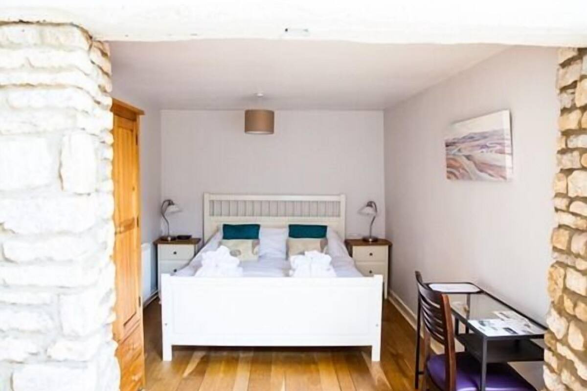 A bedroom with a bed, bedside tables, a desk, and a chair.