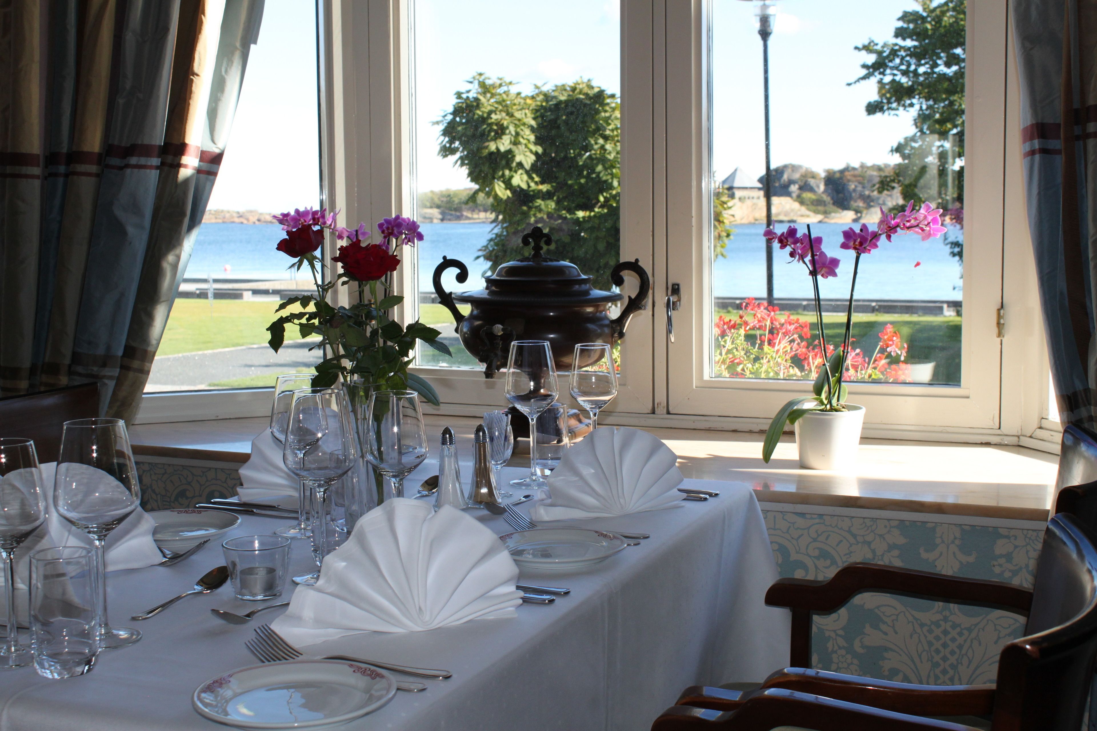 A dining table set for a meal with a view of a lake and greenery.