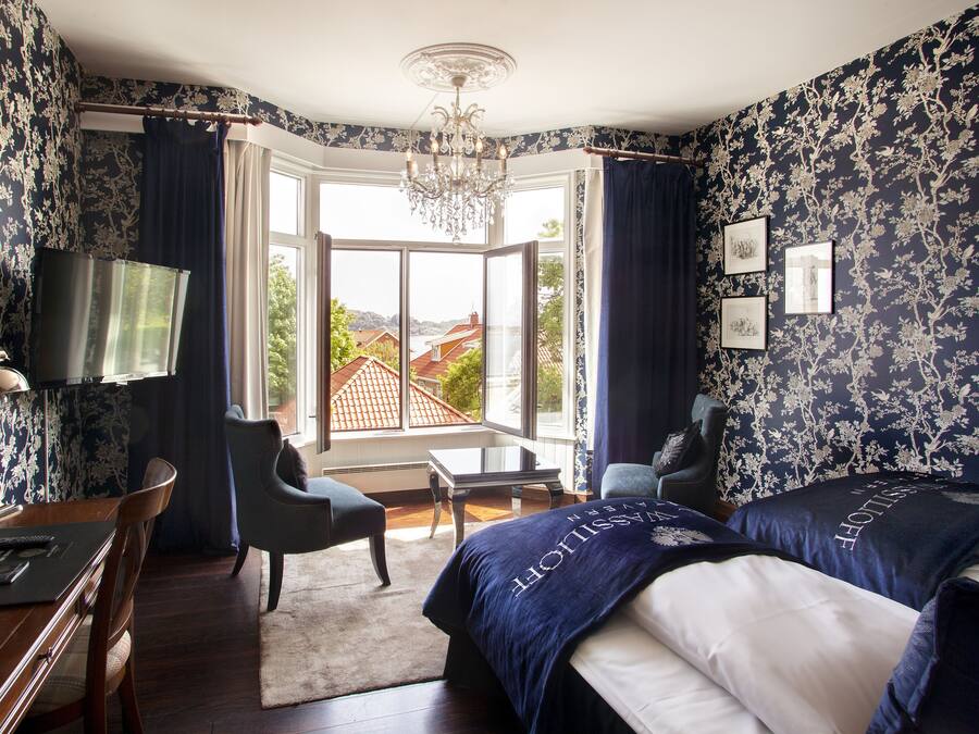 Hotelkamer met een groot bed, twee fauteuils, een bureau met lamp, een televisie en uitzicht op het exterieur.