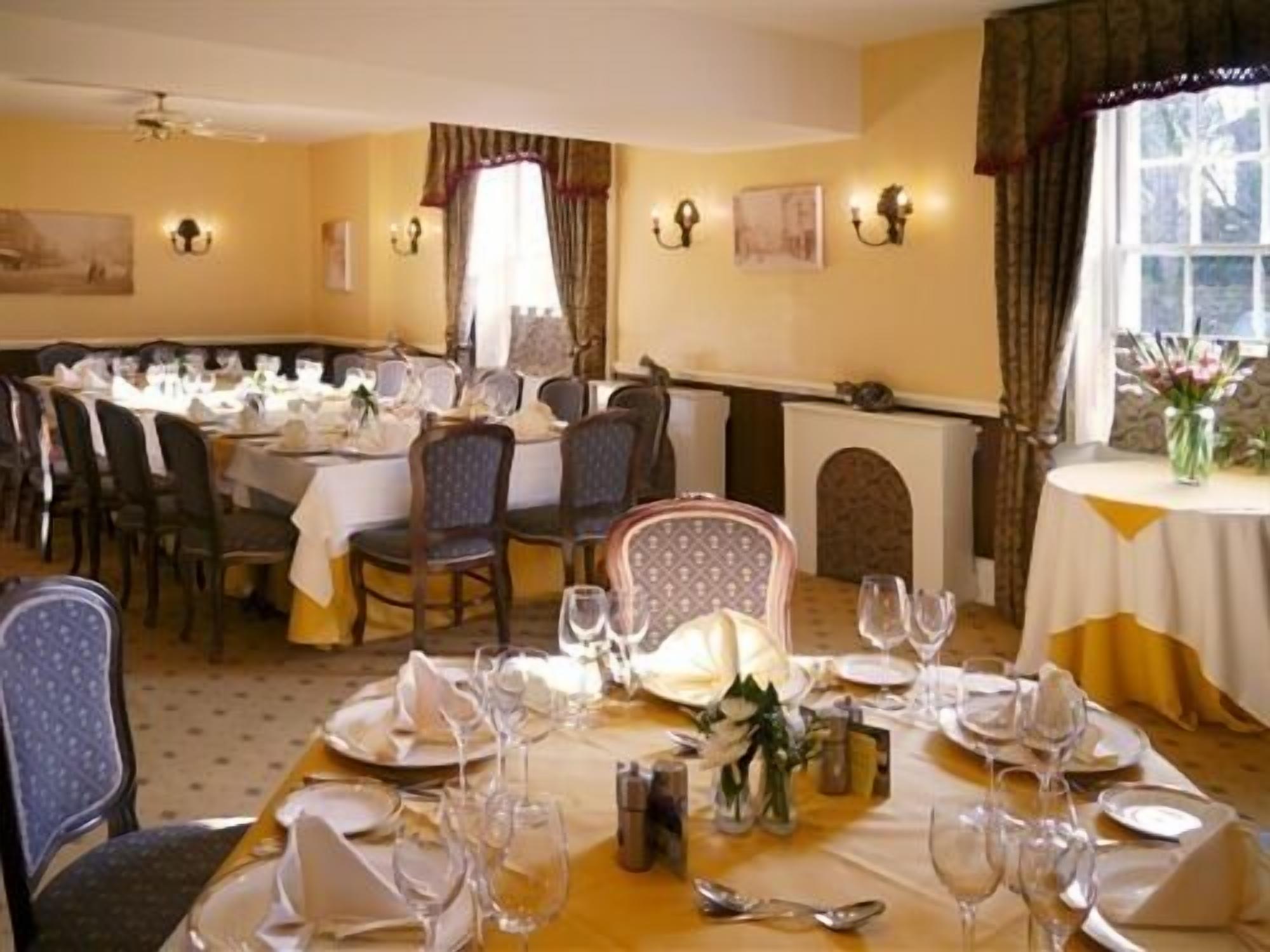 A dining area with round tables set for a meal, chairs, and a fireplace.