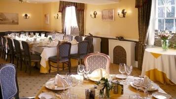 A dining area with round tables set for a meal, chairs, and a fireplace.