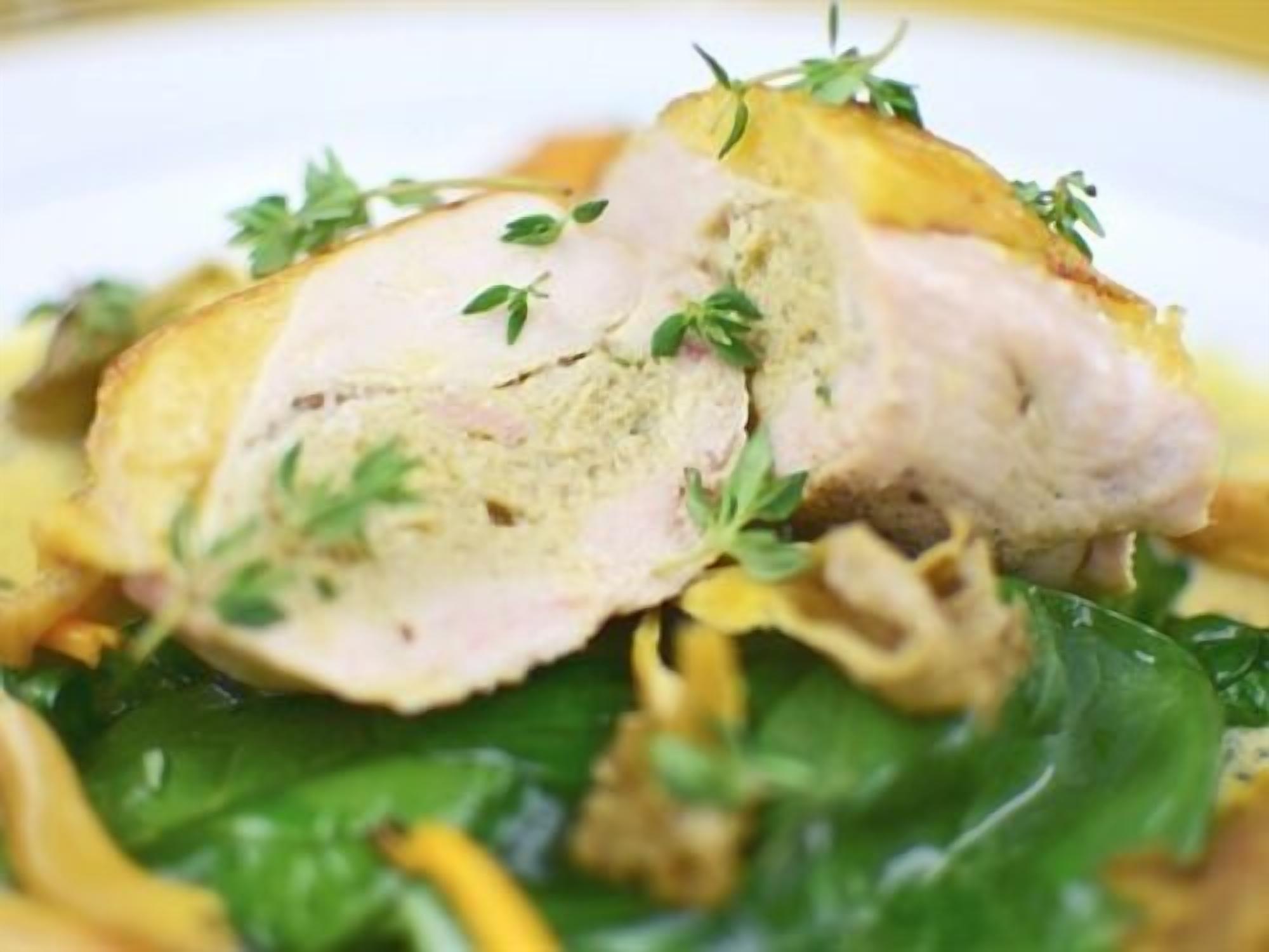 A close-up of a dish with sliced meat, greens, and a creamy sauce.
