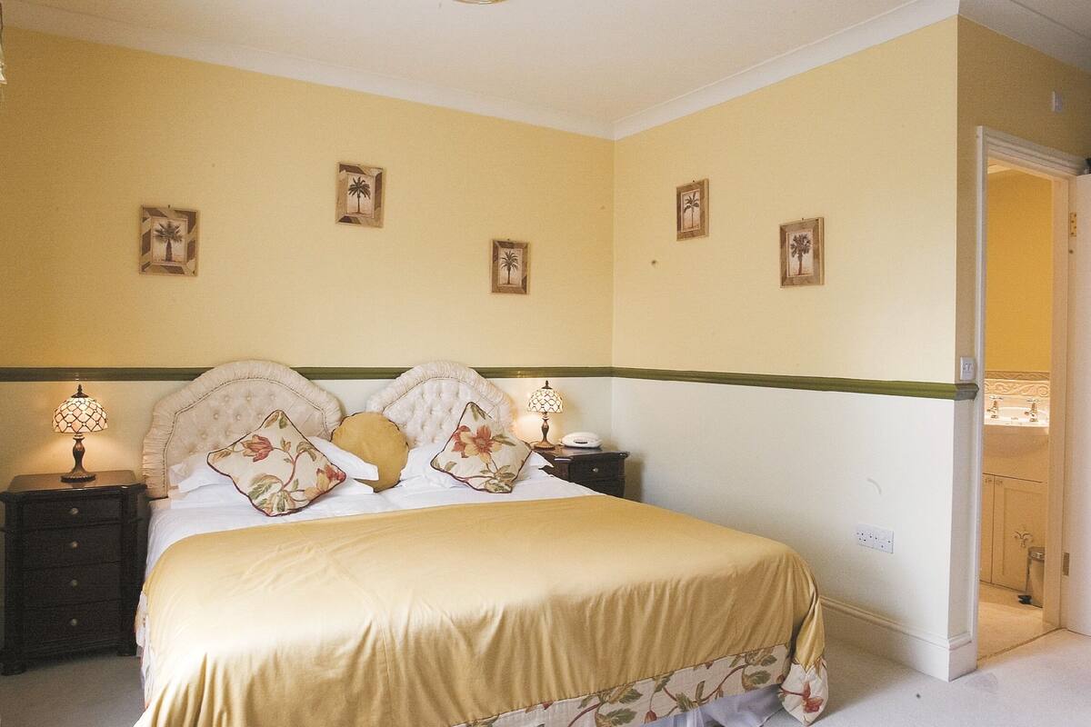 Un dormitorio con cama, mesitas de noche y lámparas de pared.