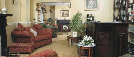 A traditional living room with a fireplace, a bar area with bottles, and patterned furniture.
