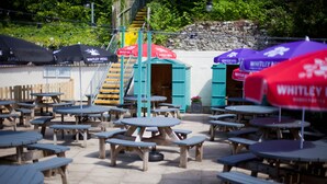 Outdoor wooden tables and benches arranged in a patio area with umbrellas labeled "WHITLEY NEILL".