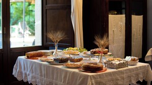 A table with various pastries and desserts, a vase with dried plants, and a cabinet in the background.