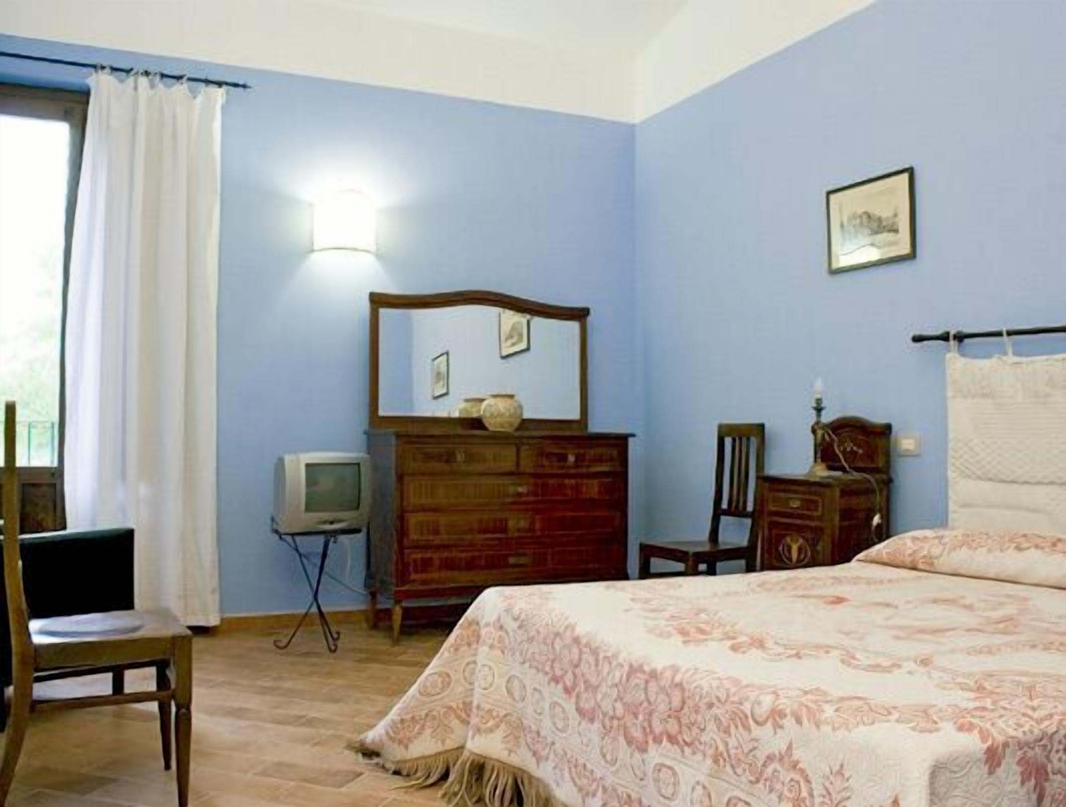 Un dormitorio con cama, cómoda, silla y televisor.