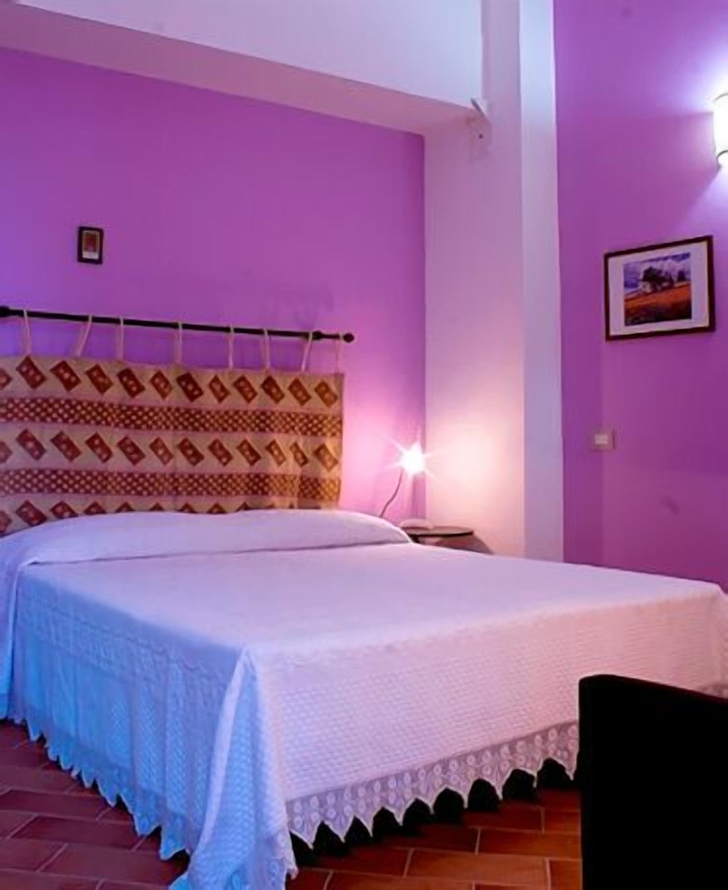 A room with a bed, a nightstand, and a wall-mounted lamp.