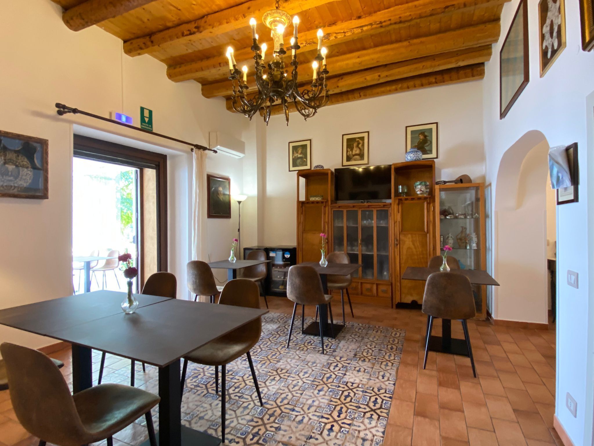 A dining area with a chandelier, wooden ceiling, and patterned floor tiles.