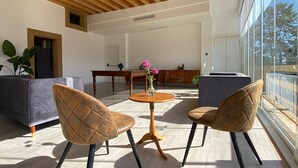 A modern living room with a wooden ceiling, a dining area, and large windows.