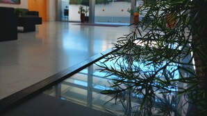 Un hall d’entrée spacieux avec une table basse en verre, un comptoir d’accueil et une plante en pot.