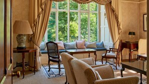 A room with a large window, a sofa, a chair, a table, and a lamp. - Penmaenuchaf Hotel (Dolgellau)