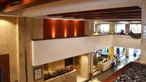 A hotel lobby with a modern design, featuring a reception desk, seating area, and a view of the city through large windows.