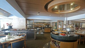 A hotel dining area with a buffet setup, a bar, and seating arrangements.