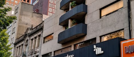 A hotel with a modern facade, multiple balconies, and a restaurant sign.