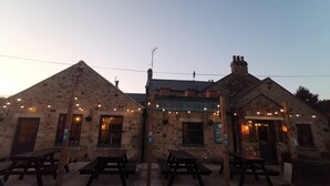 Un edificio in pietra con un cartello che riporta “The Red Well Inn”. Sono presenti tavoli da picnic all'esterno e un'indicazione per una cantina di botte e un birrificio.