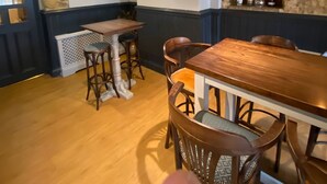 Un'accogliente sala da pranzo con un tavolo e sedie in legno, un muro in pietra e un orologio a parete.