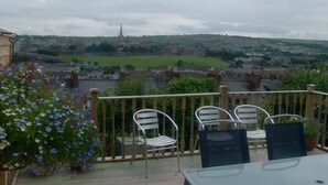A balcony with chairs and a table overlooking a town with a prominent church spire. - Serendipity House (Londonderry)