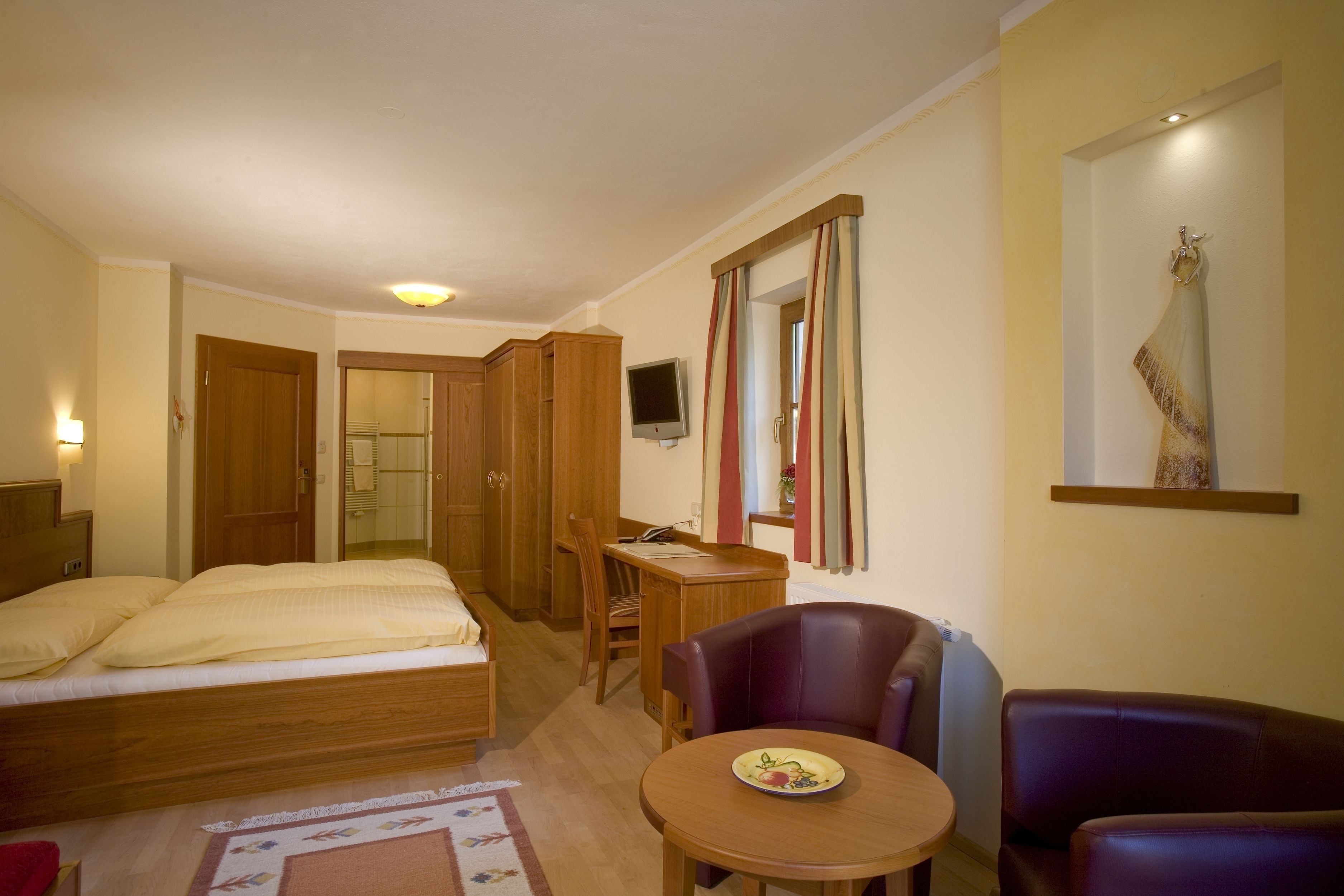 Una habitación de hotel con cama, escritorio, silla y una mesita.