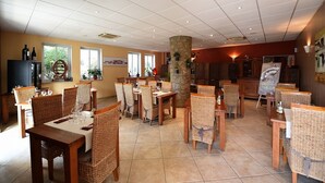 A dining area with wicker chairs and tables, a stone pillar, and artwork on the walls. - Hotel A Casa di Maria Cicilia (Ghisonaccia)