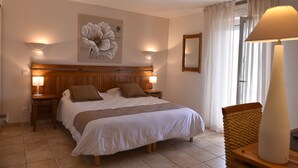 A bedroom with a large bed, two bedside tables with lamps, a wall-mounted artwork, a mirror, and a window with curtains. - Hotel A Casa di Maria Cicilia (Ghisonaccia)