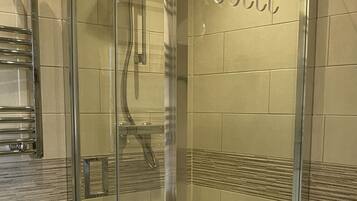 Un baño moderno con ducha envuelta en vidrio, inodoro y radiador.