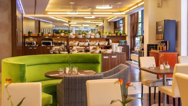 A modern hotel lobby with a green seating area, a buffet with various food items, and a coffee station. - Iris Hotel Eden - Czech Leading Hotels (Prague)