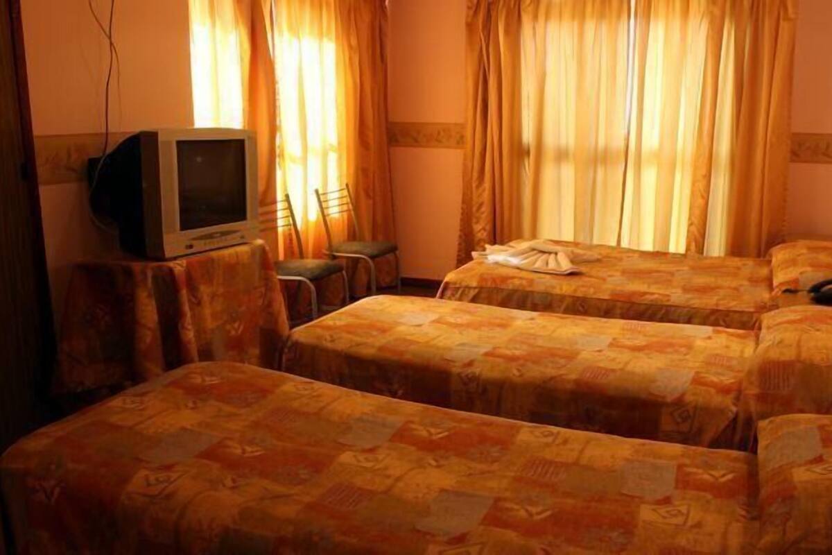 A hotel room with two beds, a television on a small table, and a chair.