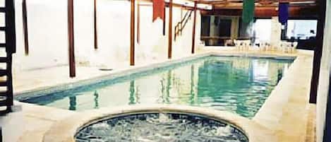A pool area with a hot tub, wooden beams, and a covered seating area.