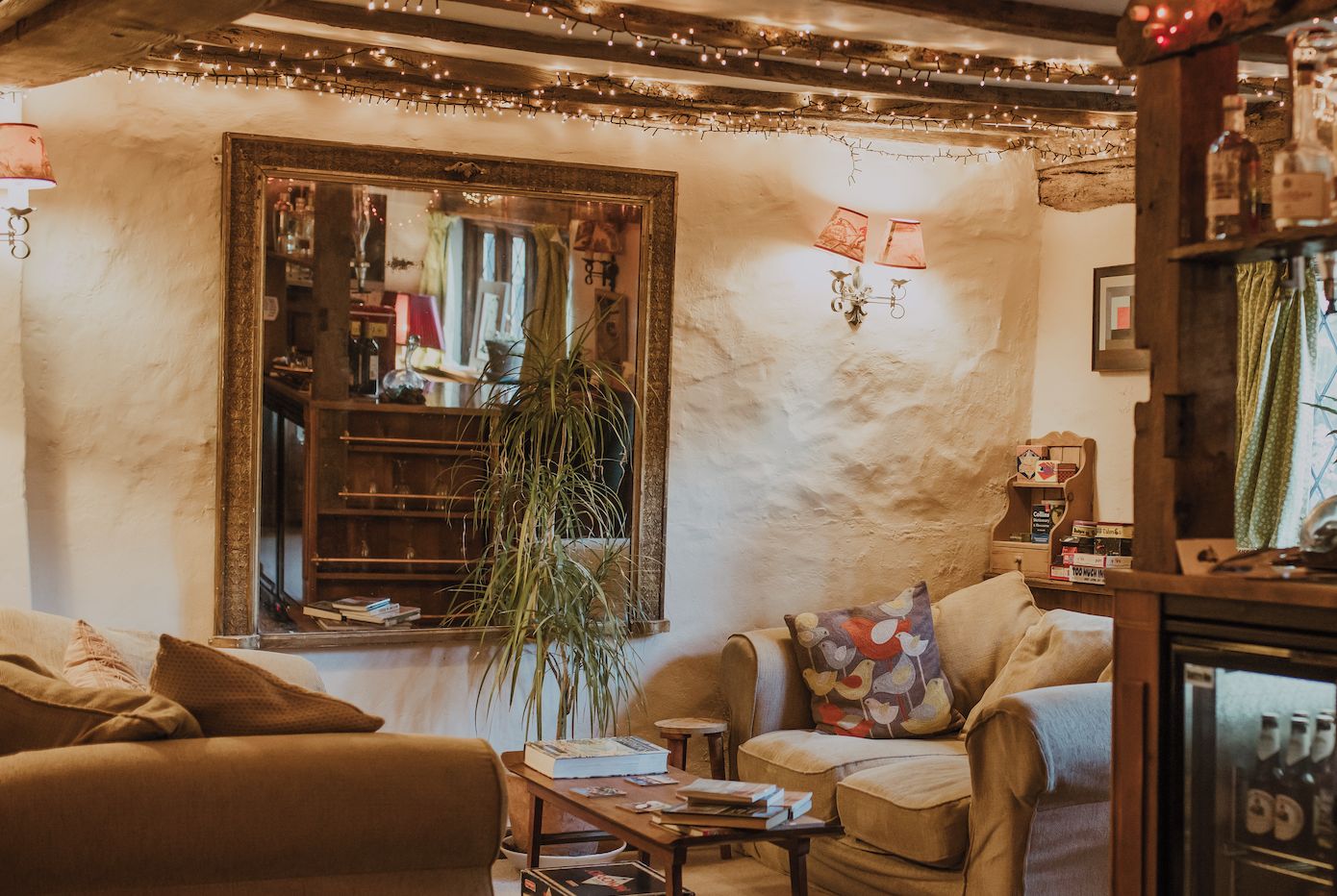 A cozy living room with a large mirror, a plant, and a coffee table with books.