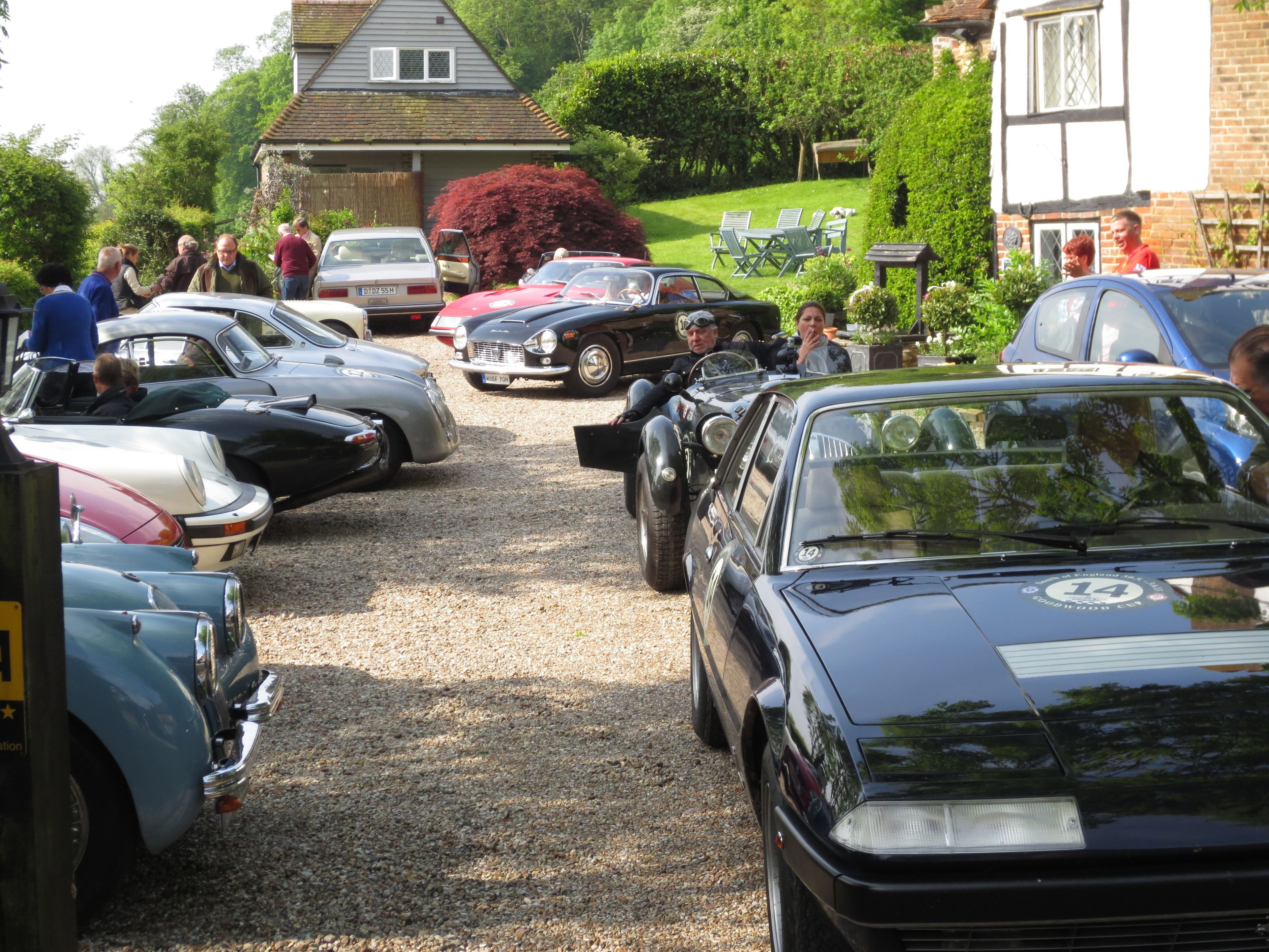 A row of vintage cars parked on a gravel driveway.