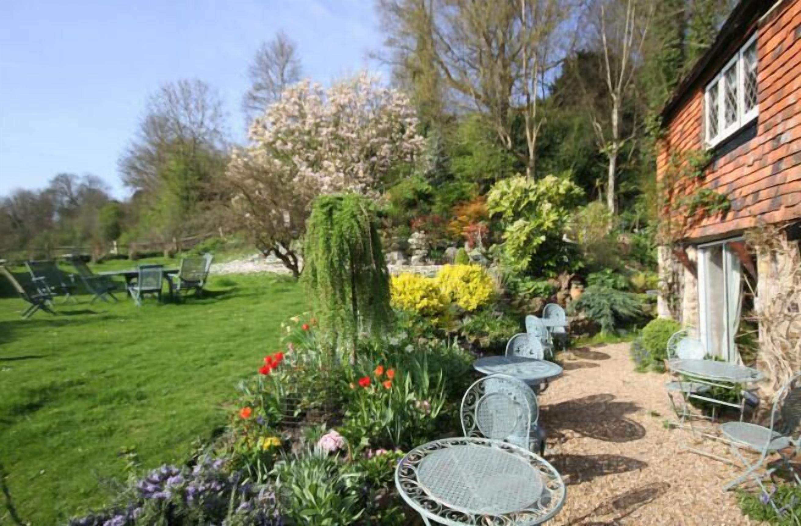 A garden with outdoor seating and a stone building.