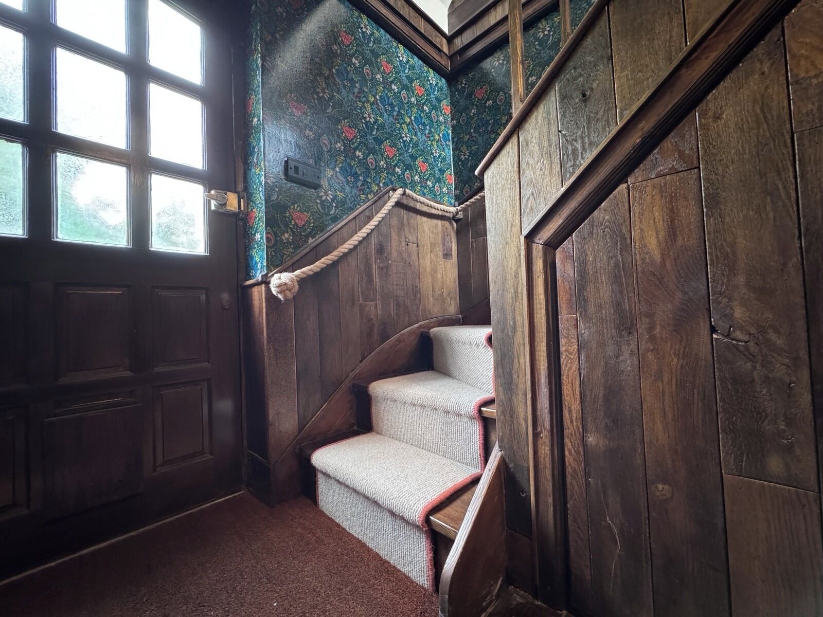 Uma escada de madeira com um papel de parede estampado e piso coberto por carpete.