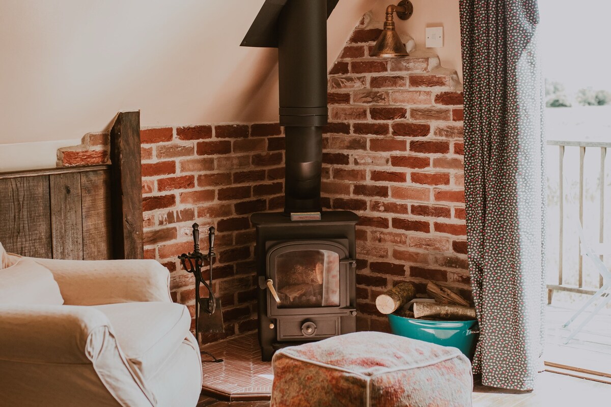 A cozy room with a brick fireplace, a wooden bench, and a white sofa.