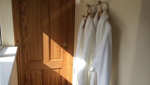 Una puerta de madera con un tirador y una cerradura de latón, y batas blancas colgadas en un perchero a la derecha.