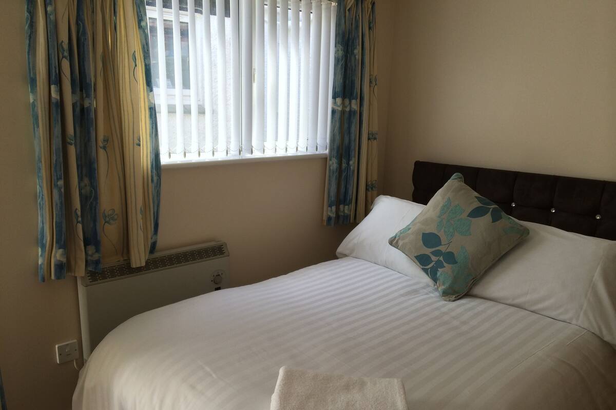 Uma cama bem arrumada com lençóis brancos, uma almofada decorativa e uma toalha dobrada na cama.
