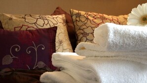 A bed with a floral-patterned pillow, a white towel, and a white flower. - The Bell (Pershore)