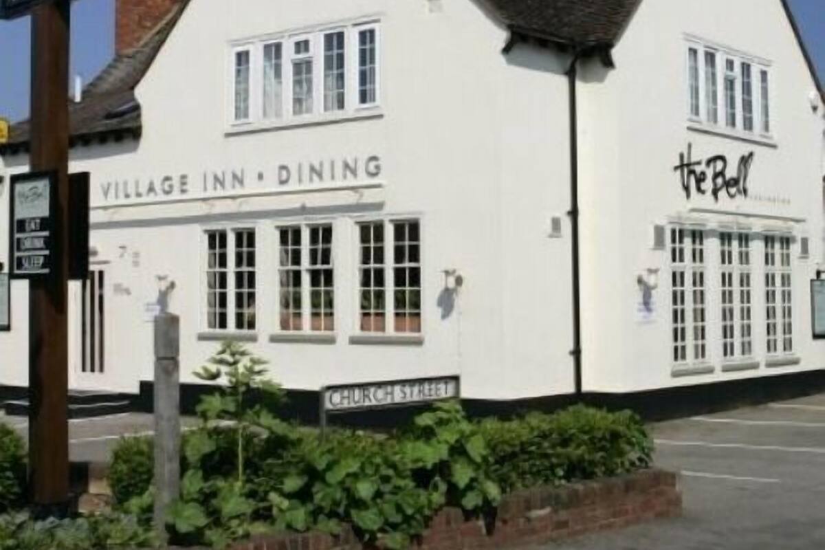 A white building with a sign reading "Village Inn - Dining" and another sign saying "The Bell".