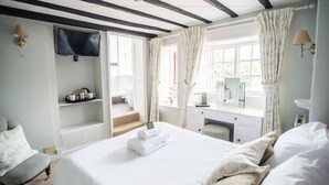 A bedroom with a bed, a desk, a chair, a television, and a window with curtains. - Findon Manor Hotel (Worthing)
