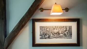 Dibujo en blanco y negro enmarcado de un lobo y un ciervo colgado en una pared, con una lámpara de pared sobre él.