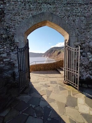 An arched stone doorway leading to a coastal area with a view of the sea and cliffs. - The Groveside Guest House (Sidmouth)