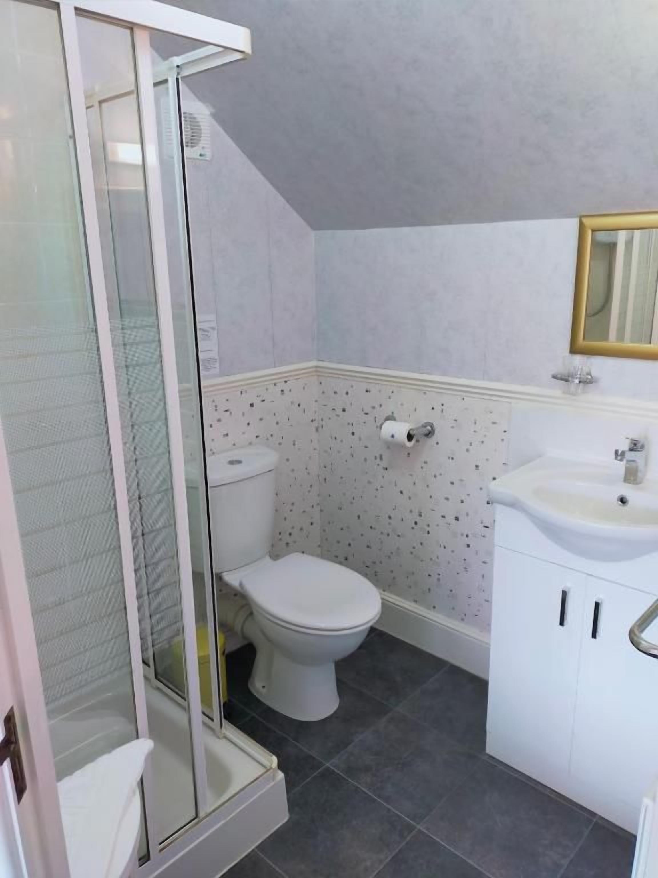 A bathroom with a shower enclosure, toilet, and sink.