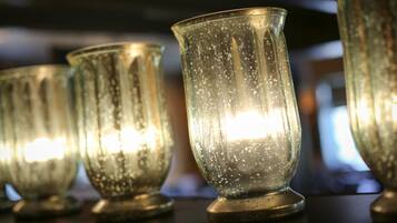 A row of clear glass candle holders with a warm light inside, placed on a dark surface.