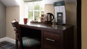 Een houten bureau met een geruit fauteuil, een koffiepot, een mok en een menubord.