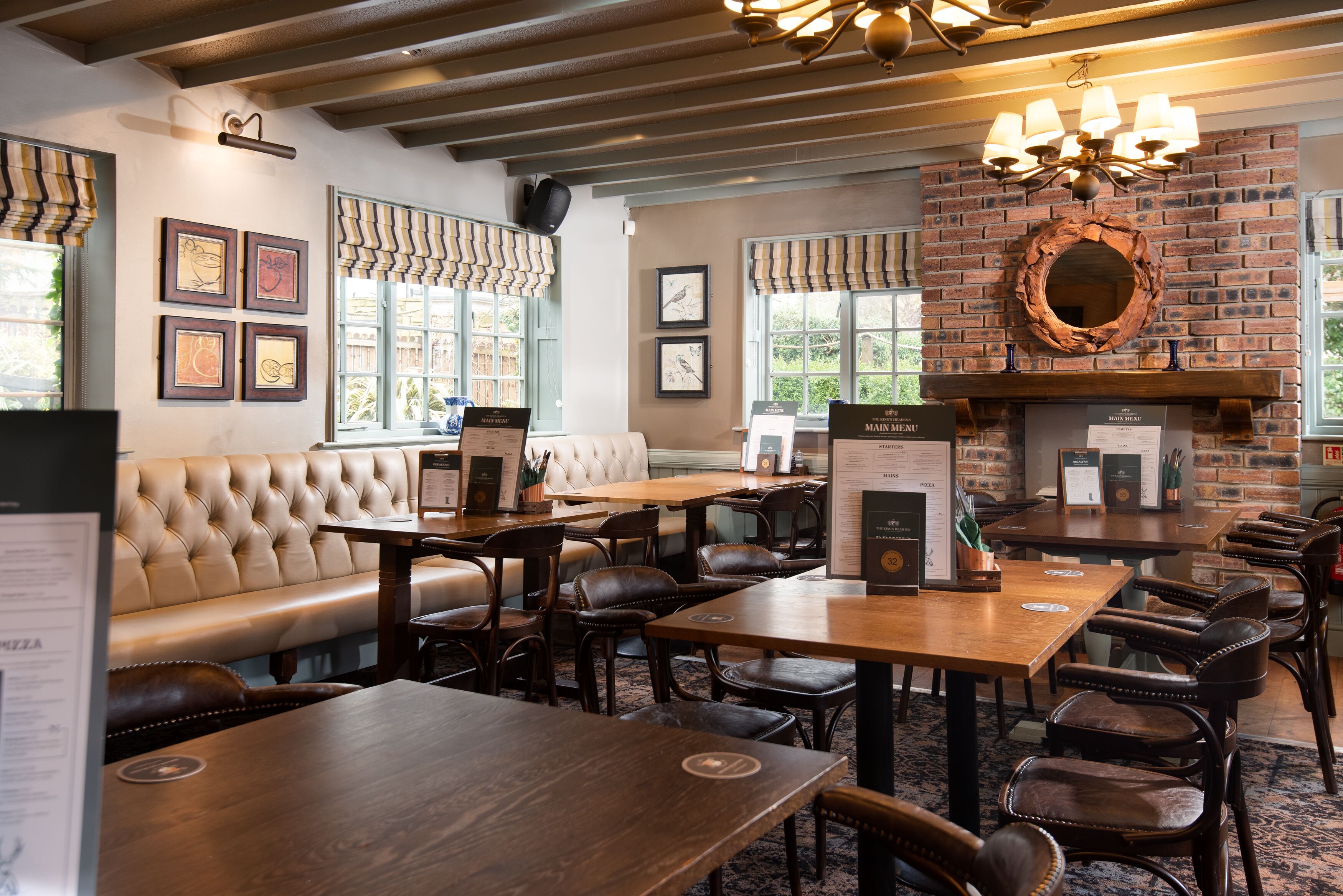 L’intérieur d’un restaurant avec des sièges en cuir, des tables en bois et une cheminée en briques.