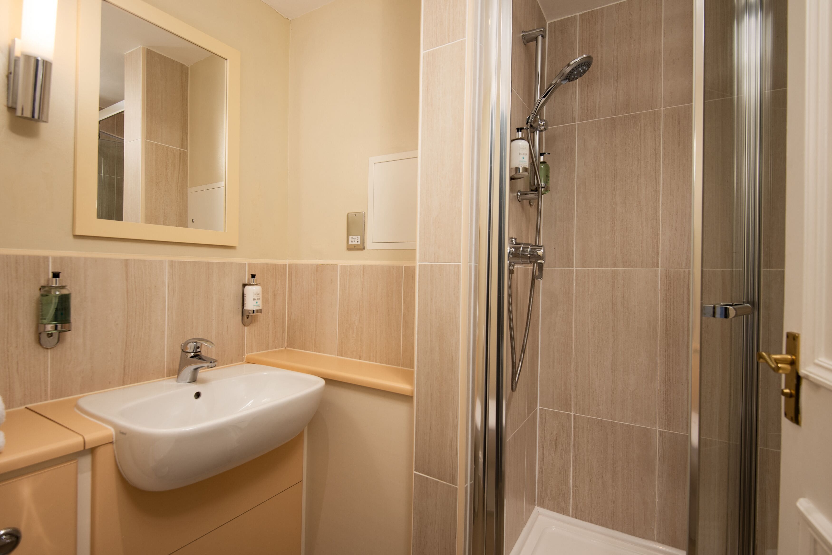 Un baño con lavamanos, espejo y ducha.